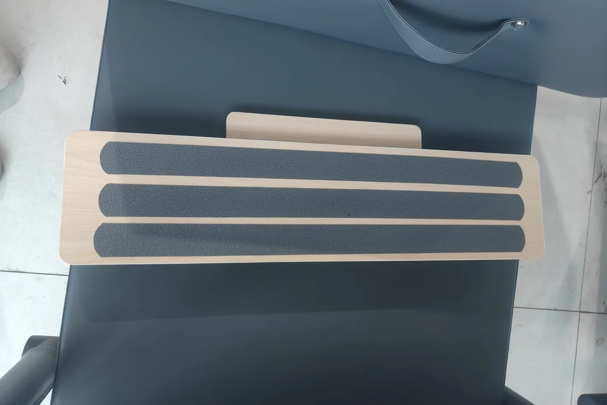 Wood platform and dark upholstery finish detail on Pilates equipment